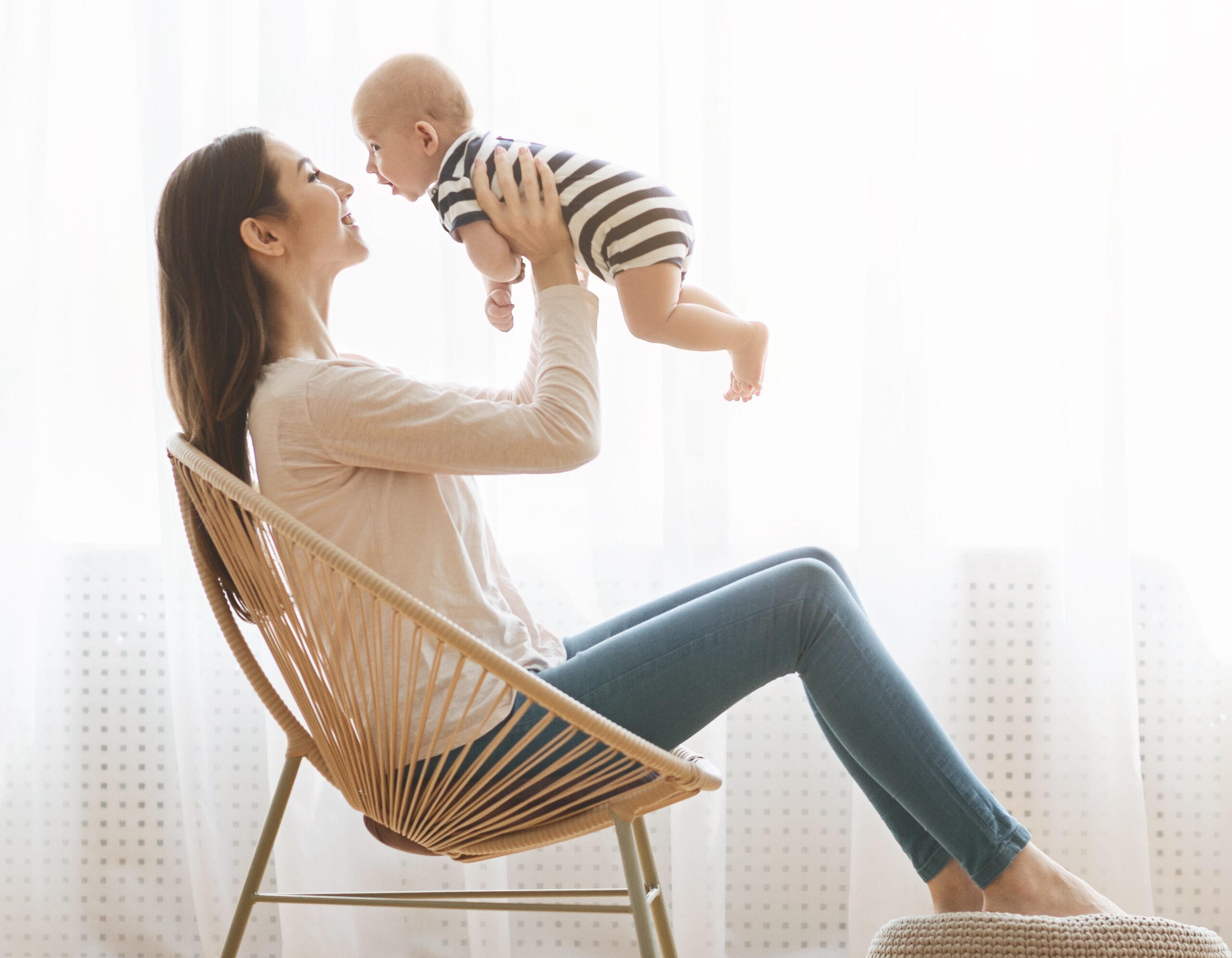 Mother sitting in chair and lifting her newborn child up